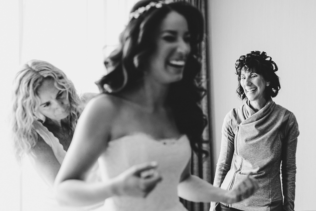 A mother watches her daughter put on a wedding dress