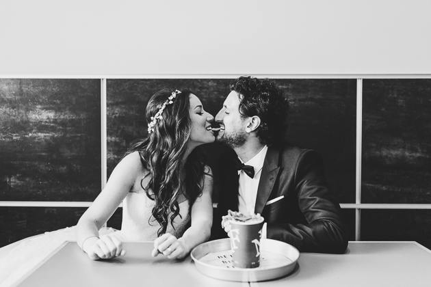 A bride and groom sharing a french fry during their wedding photo shoot 