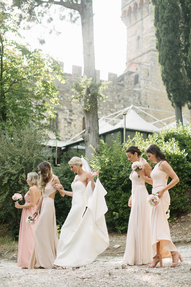 Bride and bridesmaids walking down the slippery hills of Tuscany