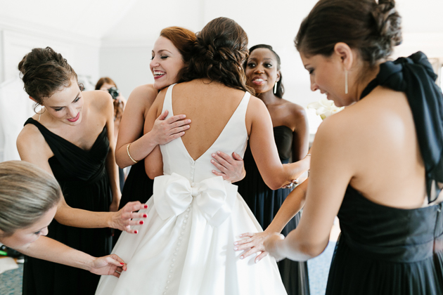 Bridesmaids giving a bride a hug after seeing her for the first time on the morning of her wedding