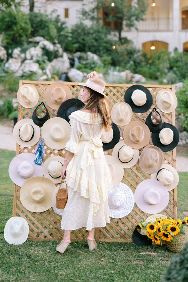 Guests pose with hat wall at garden party at the Chateau Saint-Martin, France